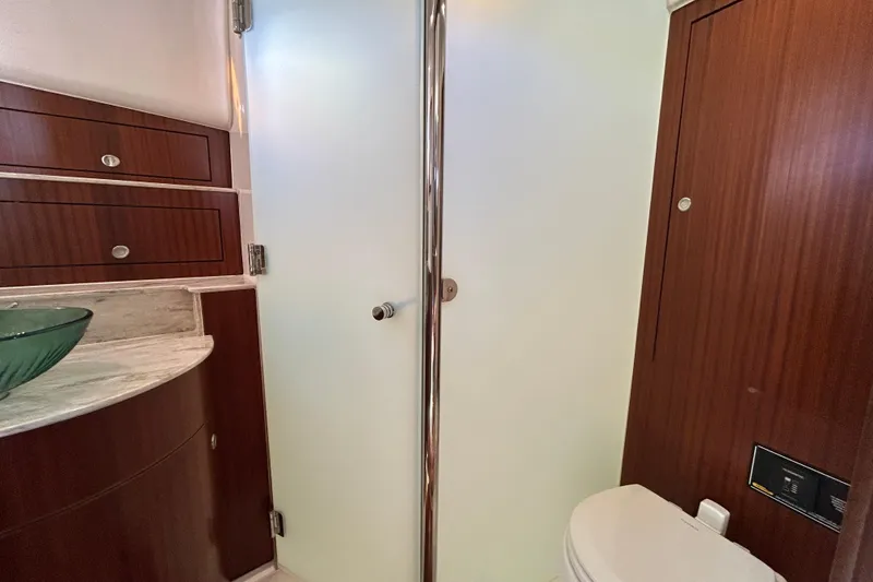 Slide: The Image of 2018 Pursuit OS 385 Offshore yacht bathroom with frosted glass door and wooden cabinetry. - 20