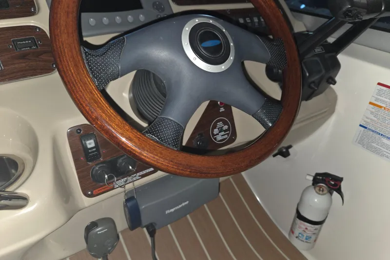 Slide: The Image of 2005 Chaparral Signature 310 boat dashboard with wooden steering wheel and safety equipment. - 13