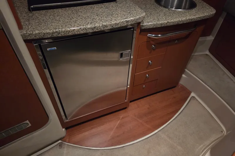 Slide: The Image of 2005 Chaparral Signature 310 interior with granite countertop, stainless fridge, and wooden cabinetry. - 19