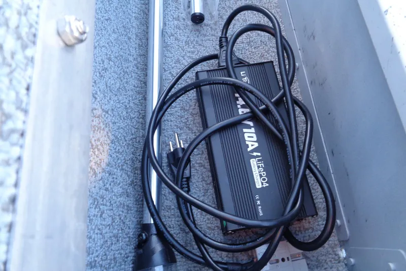 Slide: The Image of Battery charger and cables inside 2024 Lund 1400 Fury Tiller boat compartment. - 20