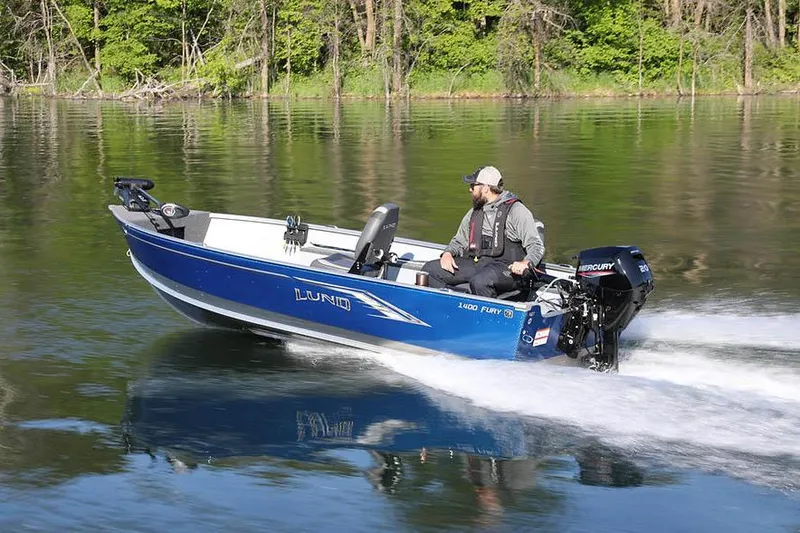 Slide: The Image of Manufacturer Provided Image: 2024 Lund 1400 Fury Tiller boat on a calm lake with a person driving. - 27