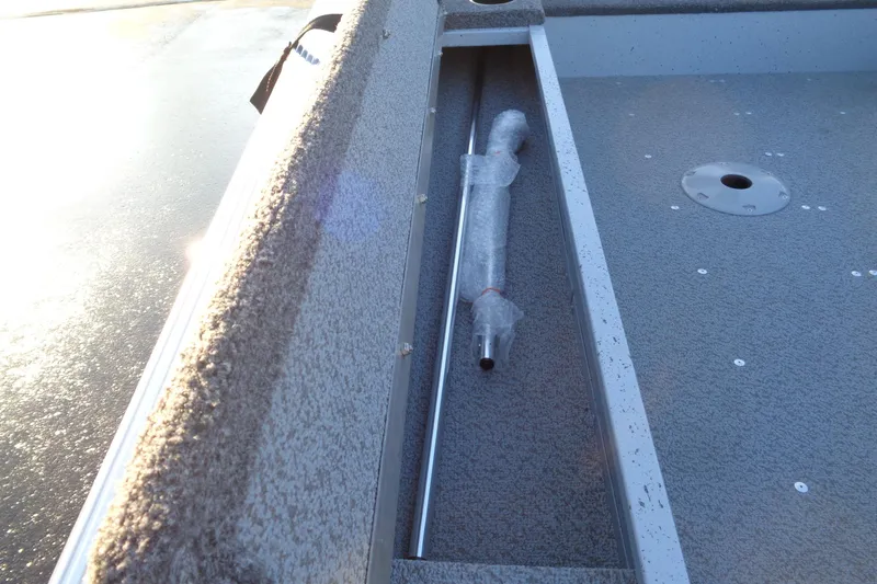 Slide: The Image of 2024 Lund 1400 Fury Tiller boat interior with storage compartment and wrapped item. - 3