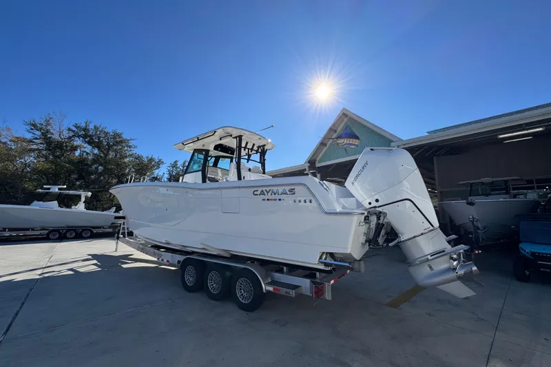 Slide: The Image of 2026 Caymas 34 CT boat on trailer under bright sun, parked near a building. - 13