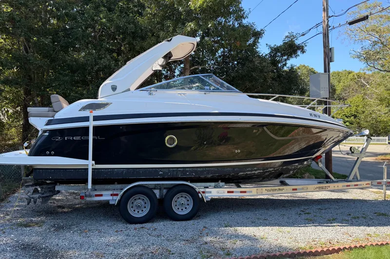 The Image of 2014 Regal 28 Express boat on trailer, parked outdoors with trees in background. - 0