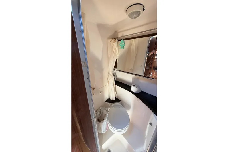 Slide: The Image of 2014 Regal 28 Express boat bathroom with toilet, mirror, and curtain. - 18