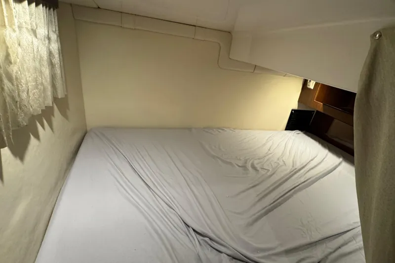 Slide: The Image of Cozy cabin bed inside 2014 Regal 28 Express boat, featuring soft lighting and curtains. - 20