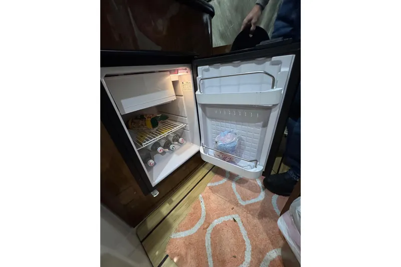 Slide: The Image of Open mini fridge inside 2014 Regal 28 Express boat, stocked with drinks and snacks. - 27