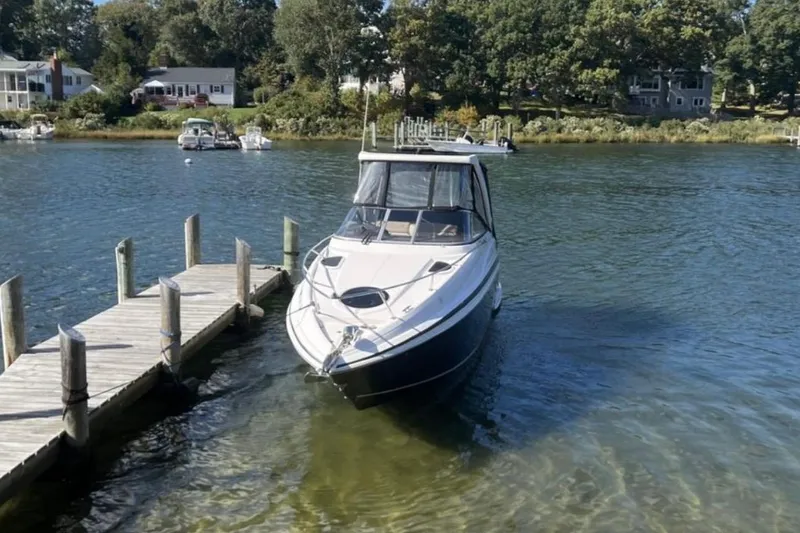 Slide: The Image of 2014 Regal 28 Express boat docked on a serene lake with surrounding trees. - 3