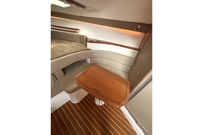 Slide: The Image of Interior of 2013 Grady-White Express 330, featuring a cozy seating area and wooden table. - 12
