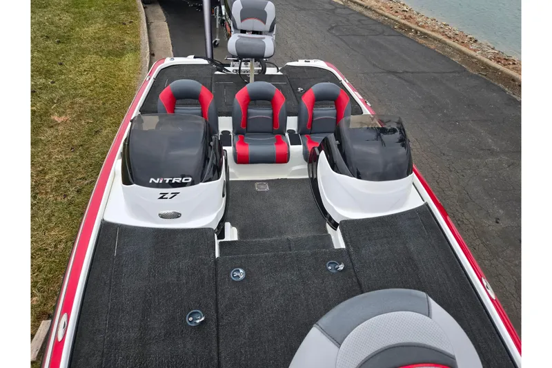 Slide: The Image of 2015 Nitro Z-7 boat with red and gray seating, docked by a lakeside. - 19