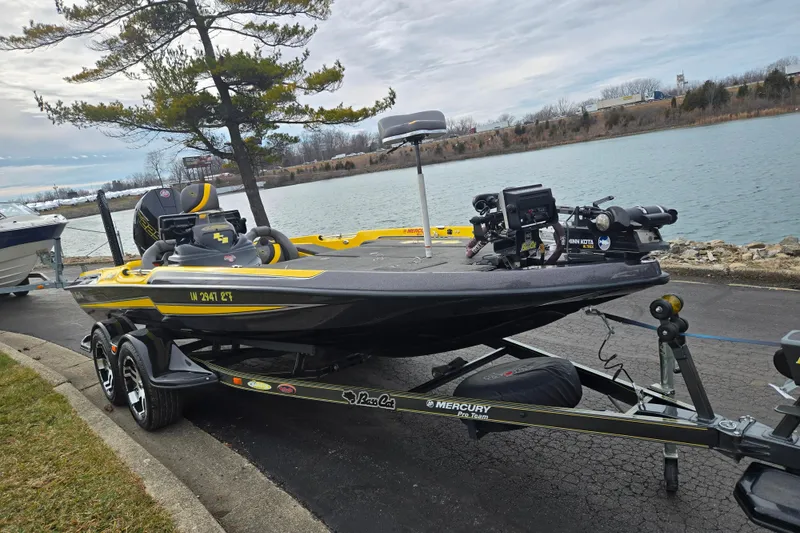 Slide: The Image of 2016 Bass Cat Caracal boat on trailer by a lakeside, featuring fishing equipment. - 10