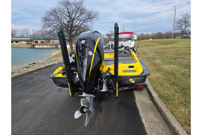 Slide: The Image of 2016 Bass Cat Caracal boat with powerful outboard motor, parked near a lake. - 2
