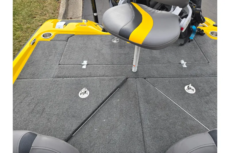 Slide: The Image of 2016 Bass Cat Caracal boat deck with gray carpet and yellow-accented seat. - 24