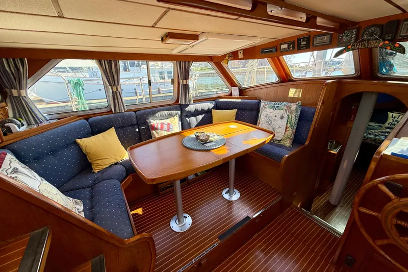 Slide: The Image of 1986 Nauticat 43 yacht interior with cozy seating and wooden dining table. - 48