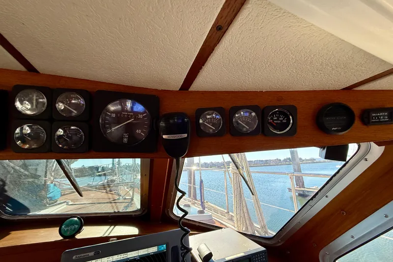 Slide: The Image of 1986 Nauticat 43 cockpit with gauges and Kenwood radio, overlooking water. - 49