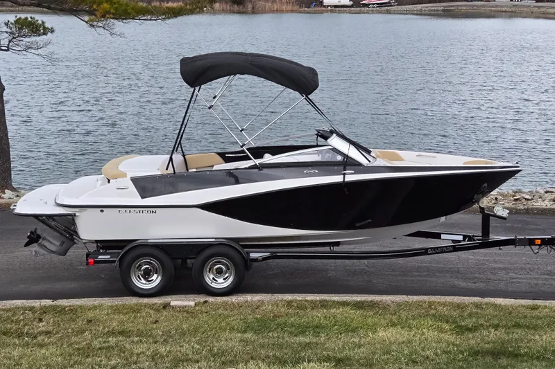 The Image of 2016 Glastron GT 205 boat on trailer by a lake, featuring sleek black and white design. - 0