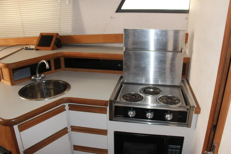 Slide: The Image of 1995 Carver 330 Mariner kitchen with stove, sink, and wooden cabinetry. - 36