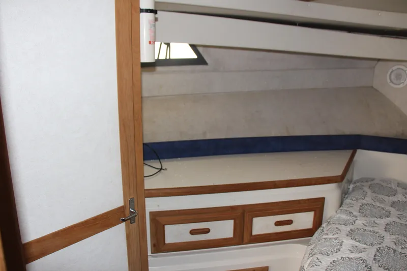 Slide: The Image of 1995 Carver 330 Mariner cabin interior with wooden drawers and patterned bedding. - 44