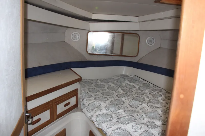 Slide: The Image of 1995 Carver 330 Mariner cabin interior with bed, wood accents, and storage drawers. - 48