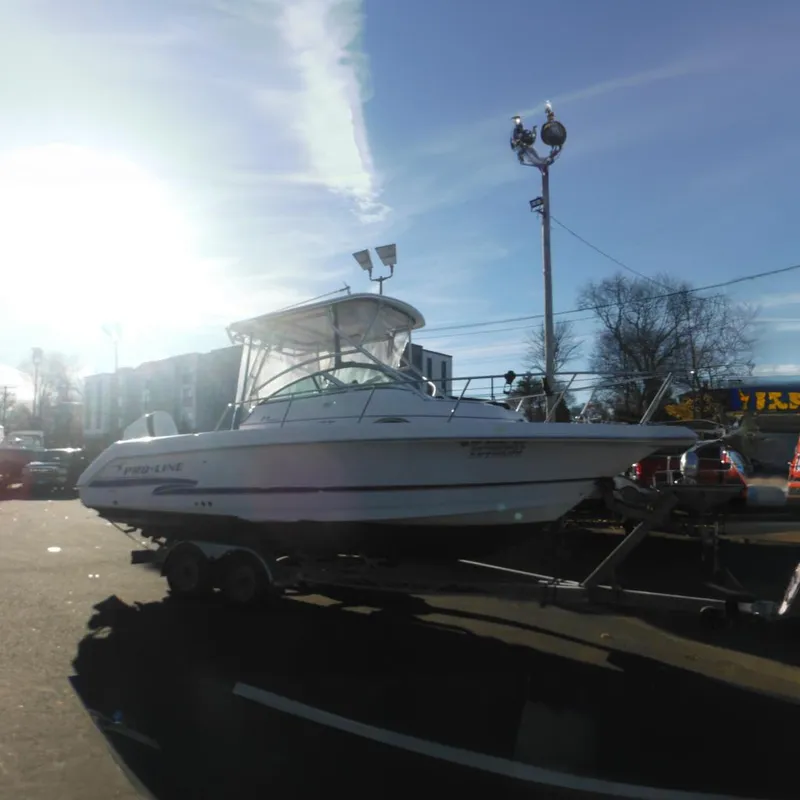 The Image of 2000 Pro-Line 23 Walkaround boat on trailer under sunny sky. - 0