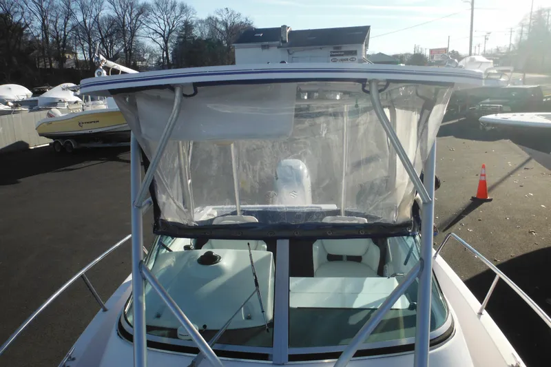 Slide: The Image of 2000 Pro-Line 23 Walkaround boat with clear canopy, docked outdoors. - 21