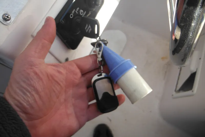 Slide: The Image of Hand holding key fob and blue plug on 2000 Pro-Line 23 Walkaround boat. - 48