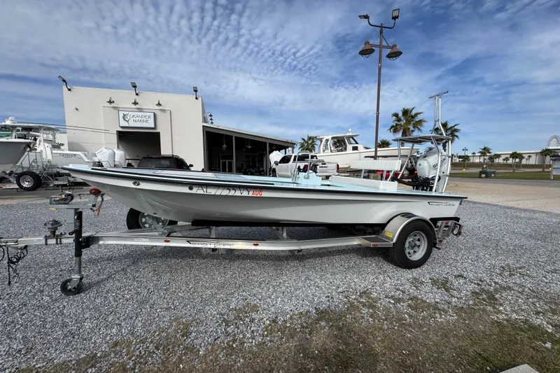Slide: The Image of 2024 East Cape EVO 18 boat on trailer at marina, under a partly cloudy sky. - 12