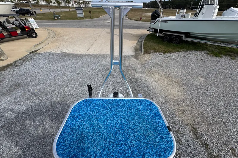 Slide: The Image of 2024 East Cape EVO 18 boat with blue deck, parked on gravel near other boats. - 30