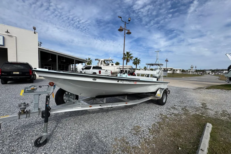 Slide: The Image of 2024 East Cape EVO 18 boat on trailer, parked outdoors under a cloudy sky. - 11