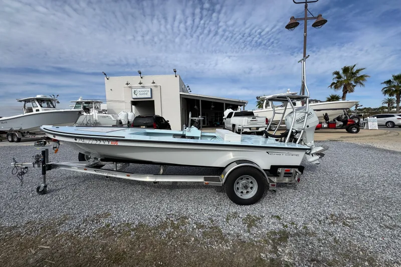 Slide: The Image of 2024 East Cape EVO 18 boat on trailer at dealership, under a cloudy sky. - 13