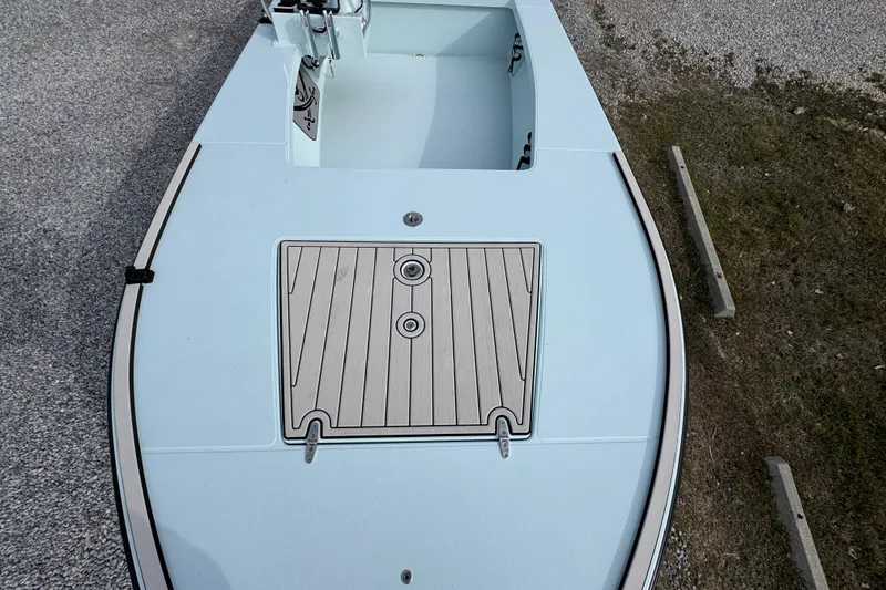 Slide: The Image of 2024 East Cape EVO 18 boat deck with storage compartment, shown on gravel surface. - 18