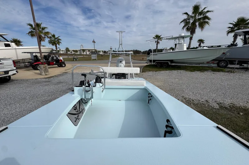 Slide: The Image of 2024 East Cape EVO 18 boat, light blue interior, parked outdoors with palm trees. - 19