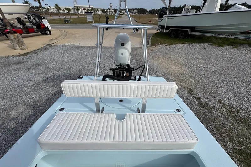 Slide: The Image of 2024 East Cape EVO 18 boat with white seating and motor, parked on gravel. - 23