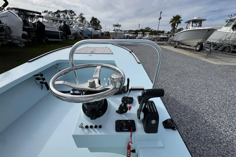 Slide: The Image of 2024 East Cape EVO 18 boat steering console with controls, parked among other boats. - 25