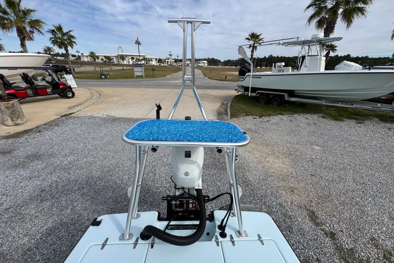 Slide: The Image of 2024 East Cape EVO 18 boat with blue deck, parked near palm trees and trailers. - 26