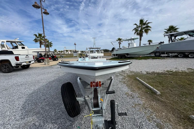 Slide: The Image of 2024 East Cape EVO 18 boat on trailer, parked outdoors with palm trees and other boats nearby. - 9