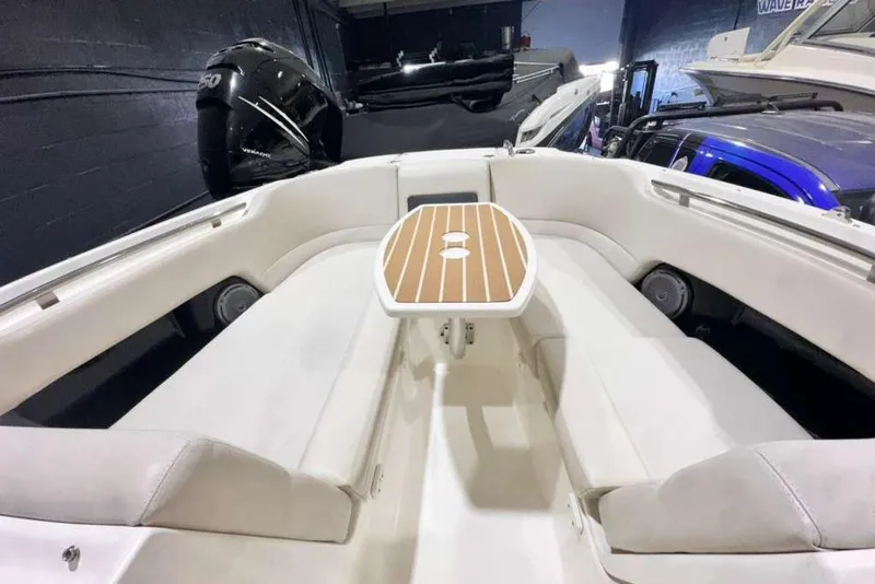 Slide: The Image of 2018 Boston Whaler 230 Vantage boat interior with seating and table, featuring a powerful engine. - 6