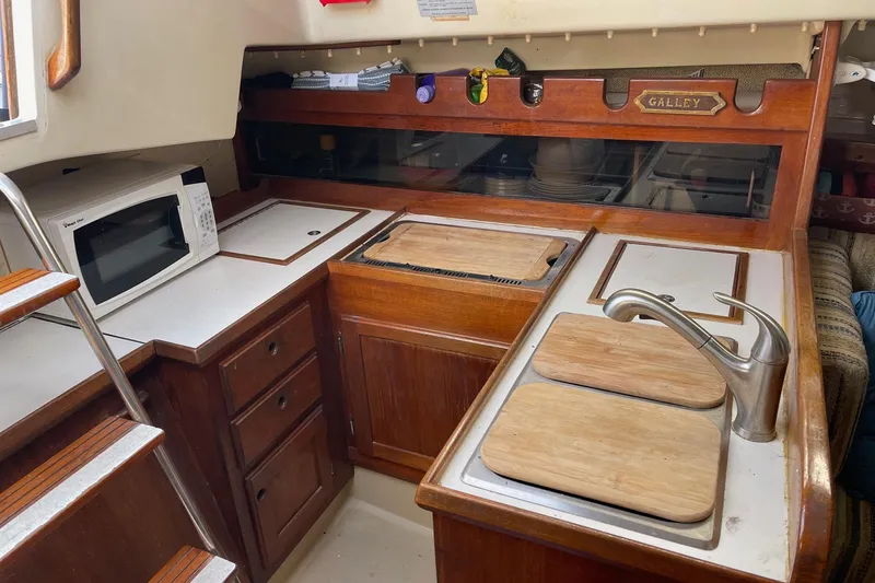 Slide: The Image of 1982 O'Day 34 sailboat galley with wooden cabinets, sink, and microwave. - 31