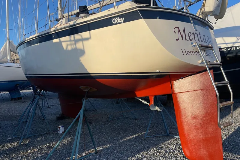 Slide: The Image of 1982 O'Day 34 sailboat on stands, red hull, ladder attached, in a boatyard. - 8