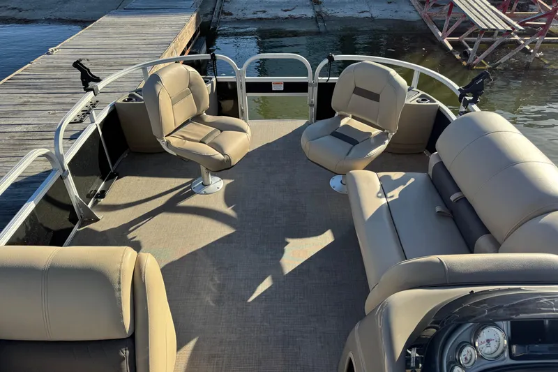 Slide: The Image of 2022 Sun Tracker Fishin' Barge 20 DLX interior with beige seating and fishing rod holders. - 9