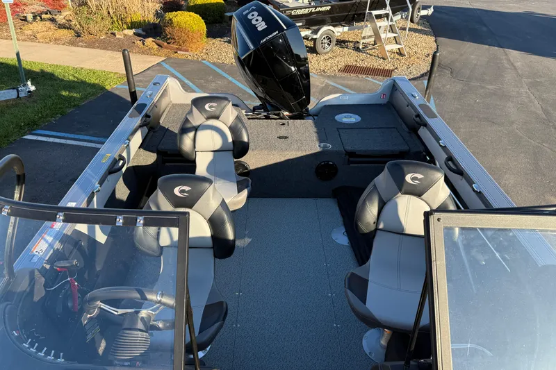 Slide: The Image of 2026 Crestliner 1850 Super Hawk interior with seating and motor, parked outdoors. - 13