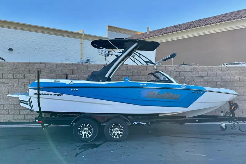 The Image of 2023 Malibu Wakesetter 21 LX boat on trailer, blue and white design. - 0