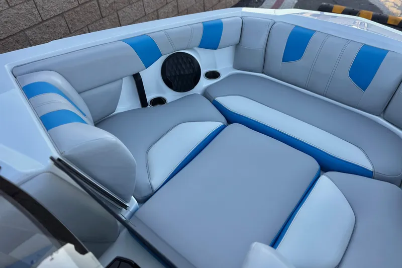 Slide: The Image of 2023 Malibu Wakesetter 21 LX interior with blue and gray seating, cup holders, and speaker. - 13
