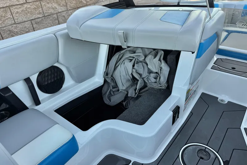 Slide: The Image of 2023 Malibu Wakesetter 21 LX interior storage compartment with open seat and stored items. - 22