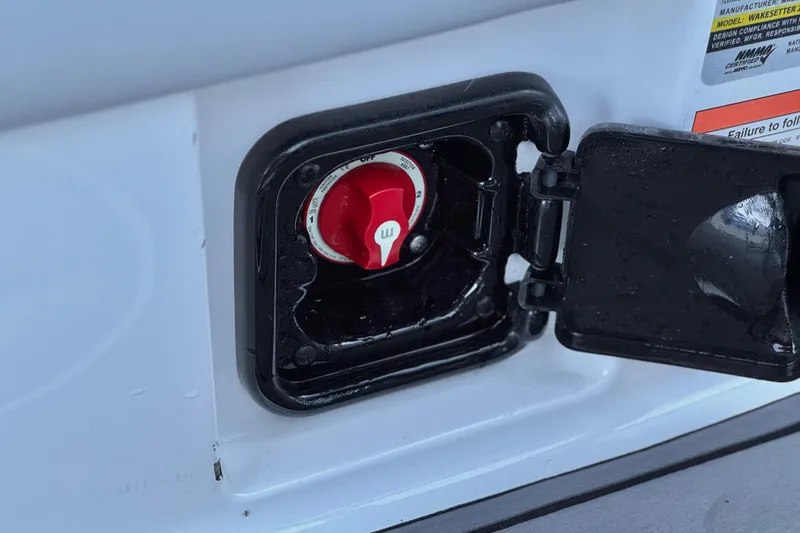 Slide: The Image of 2023 Malibu Wakesetter 21 LX battery switch compartment with red dial and black cover. - 24