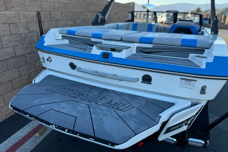 Slide: The Image of 2023 Malibu Wakesetter 21 LX boat with blue and gray seating, rear view. - 5
