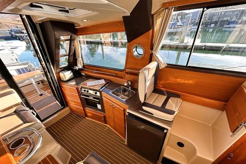 Slide: The Image of 2019 Ranger Tugs R-29 CB interior with kitchen, seating, and waterfront view. - 19