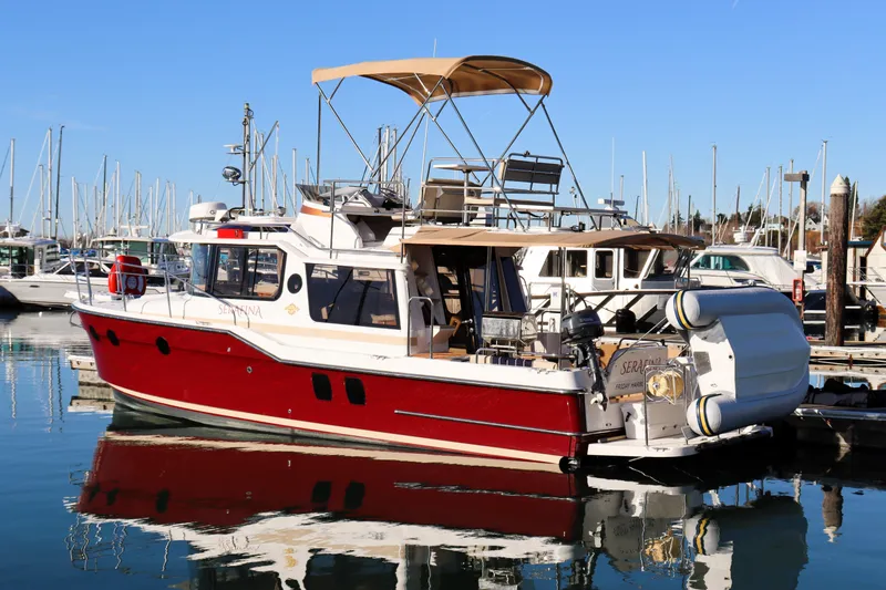 Slide: The Image of 2019 Ranger Tugs R-29 CB boat docked in marina, featuring red hull and canopy. - 2