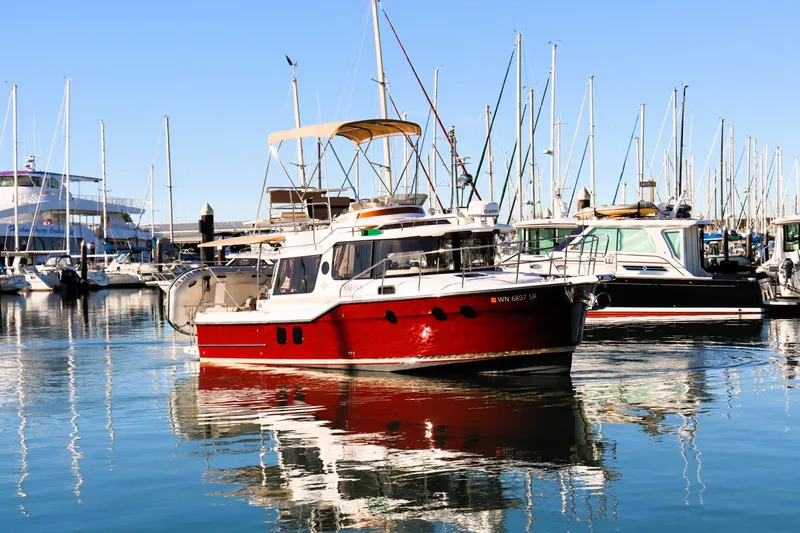 Slide: The Image of 2019 Ranger Tugs R-29 CB boat docked in a marina, surrounded by sailboats. - 3