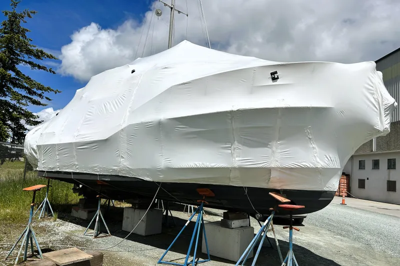 Slide: The Image of 2019 Ranger Tugs R-29 CB boat covered in white tarp, supported on stands outdoors. - 40